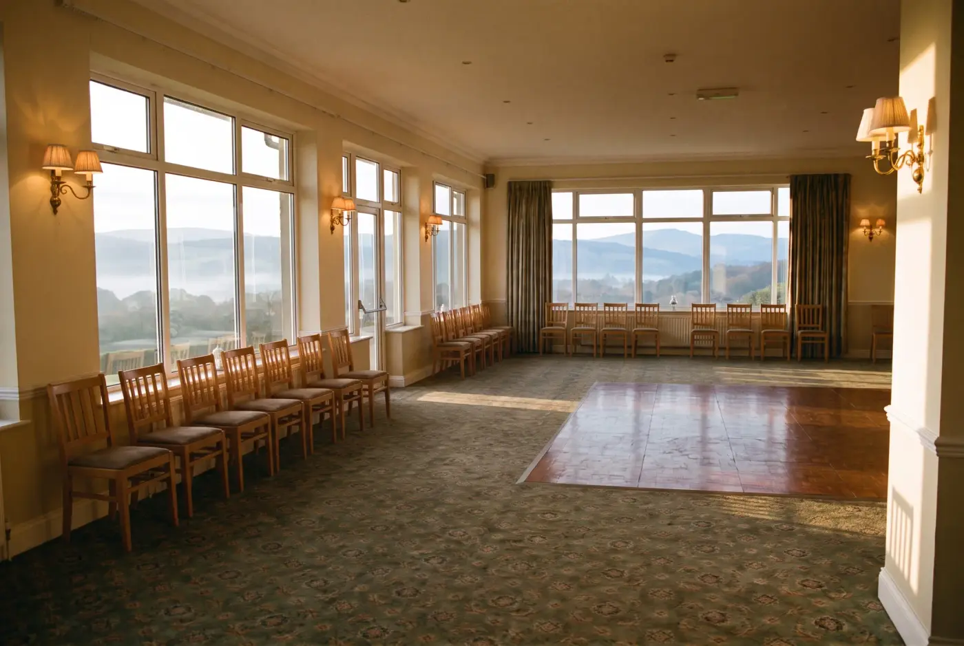 The function room set for nothing: chairs along the windows, the parquet floor bare, the valley visible through every window