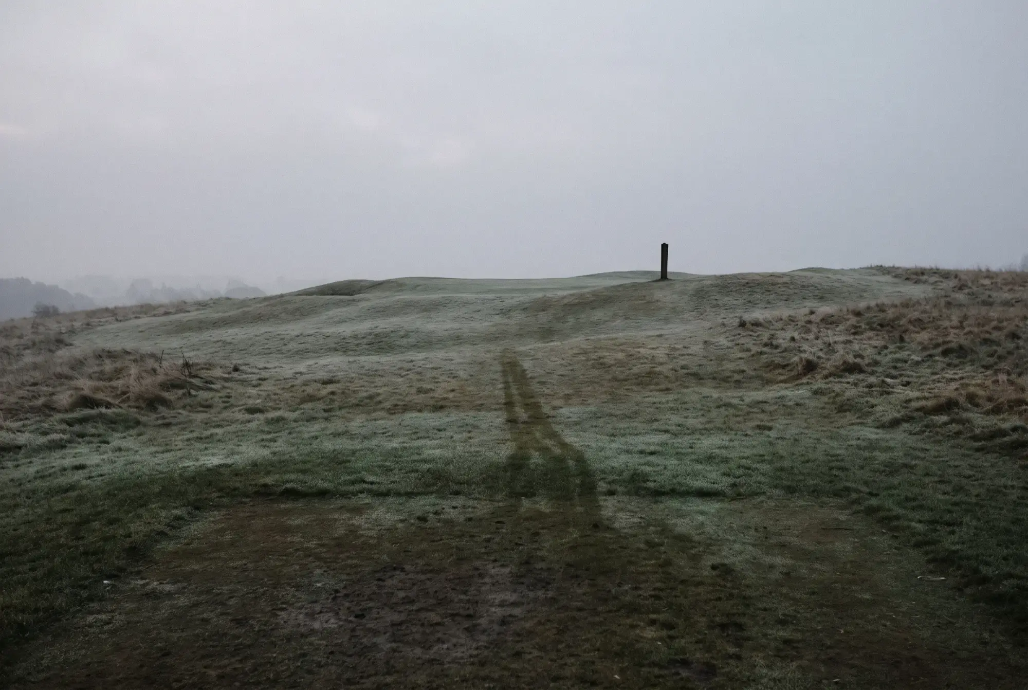 The blind tee shot on the seventh: a single marker post on the crest of a rise, frost on the grass, nothing else in view