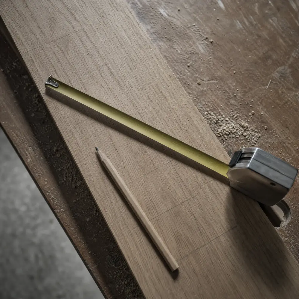 A carpenter’s pencil marking a scribe line where a wardrobe end panel meets an out-of-plumb wall